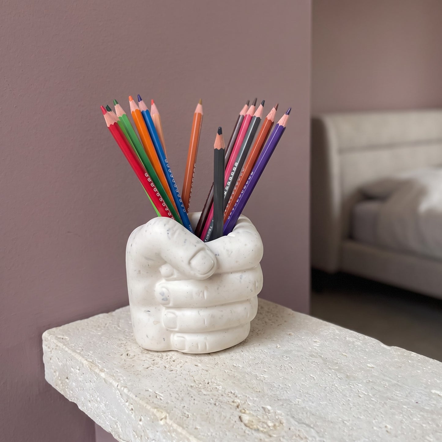 Pot à crayons Main avec crayons de couleur sur une étagère en pierre claire dans une chambre contemporaine