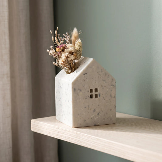 Petit vase Maison avec fleurs séchées sur une étagère devant un mur vert
