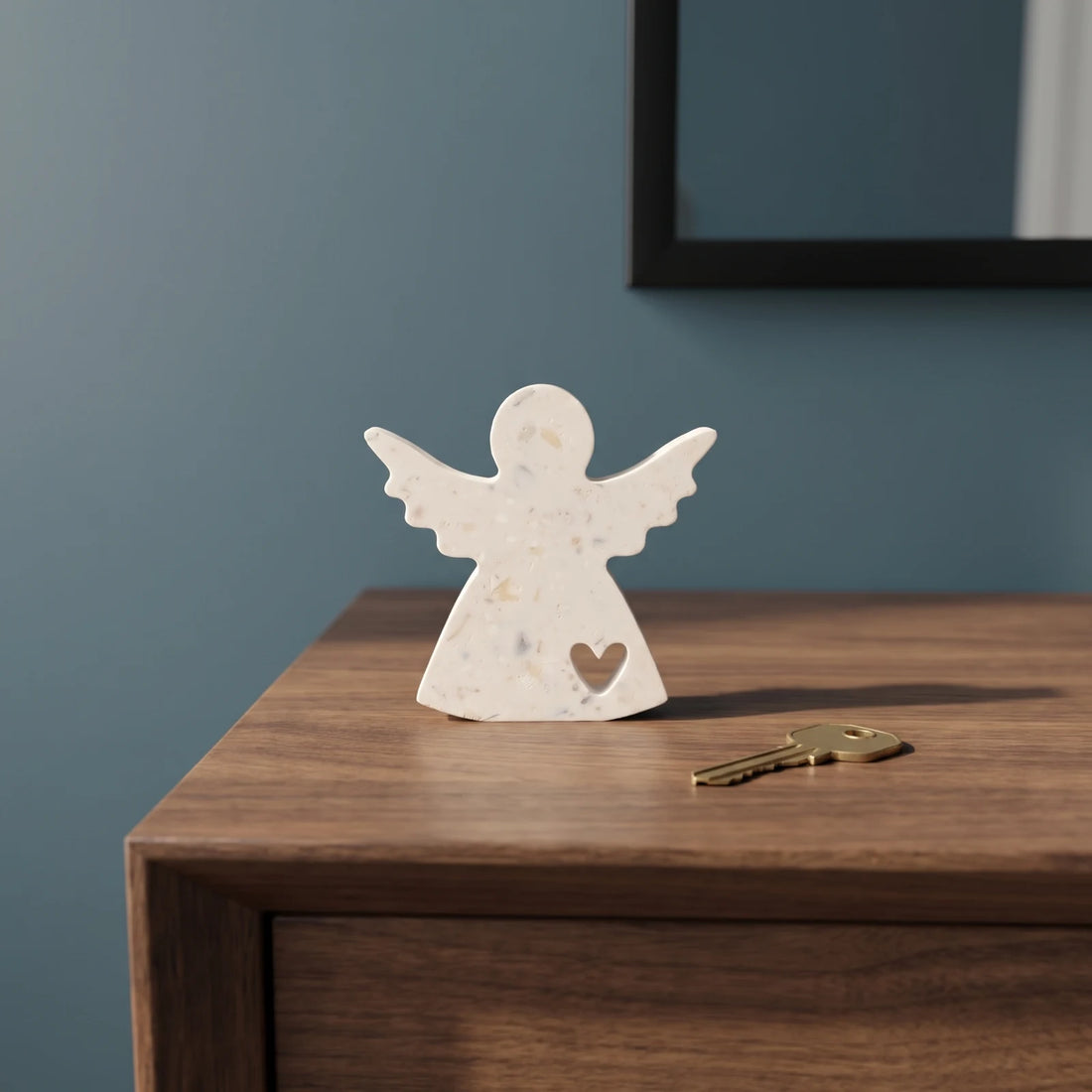 Ange S au cœur ajouré posé sur une console en bois devant un mur bleu