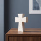 Croix évasée à poser sur une console en noyer devant un mur bleu