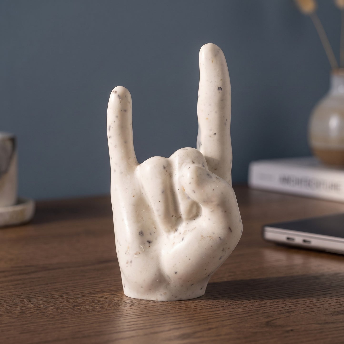 Main rock artisanale sur un bureau en bois devant un mur bleu