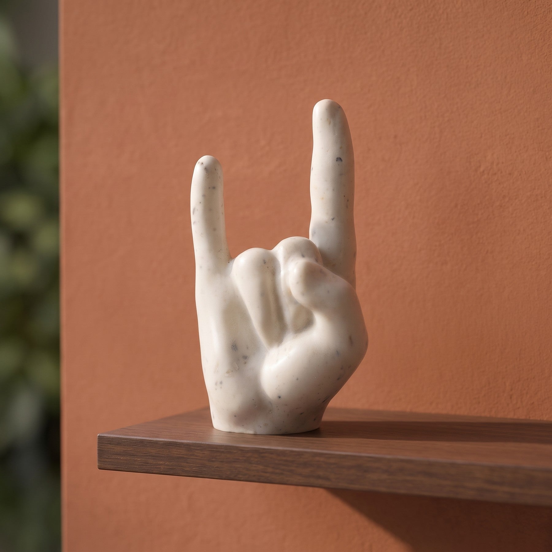 Main rock en coquillages recyclés sur une étagère devant un mur terracotta