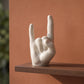 Main rock en coquillages recyclés sur une étagère devant un mur terracotta