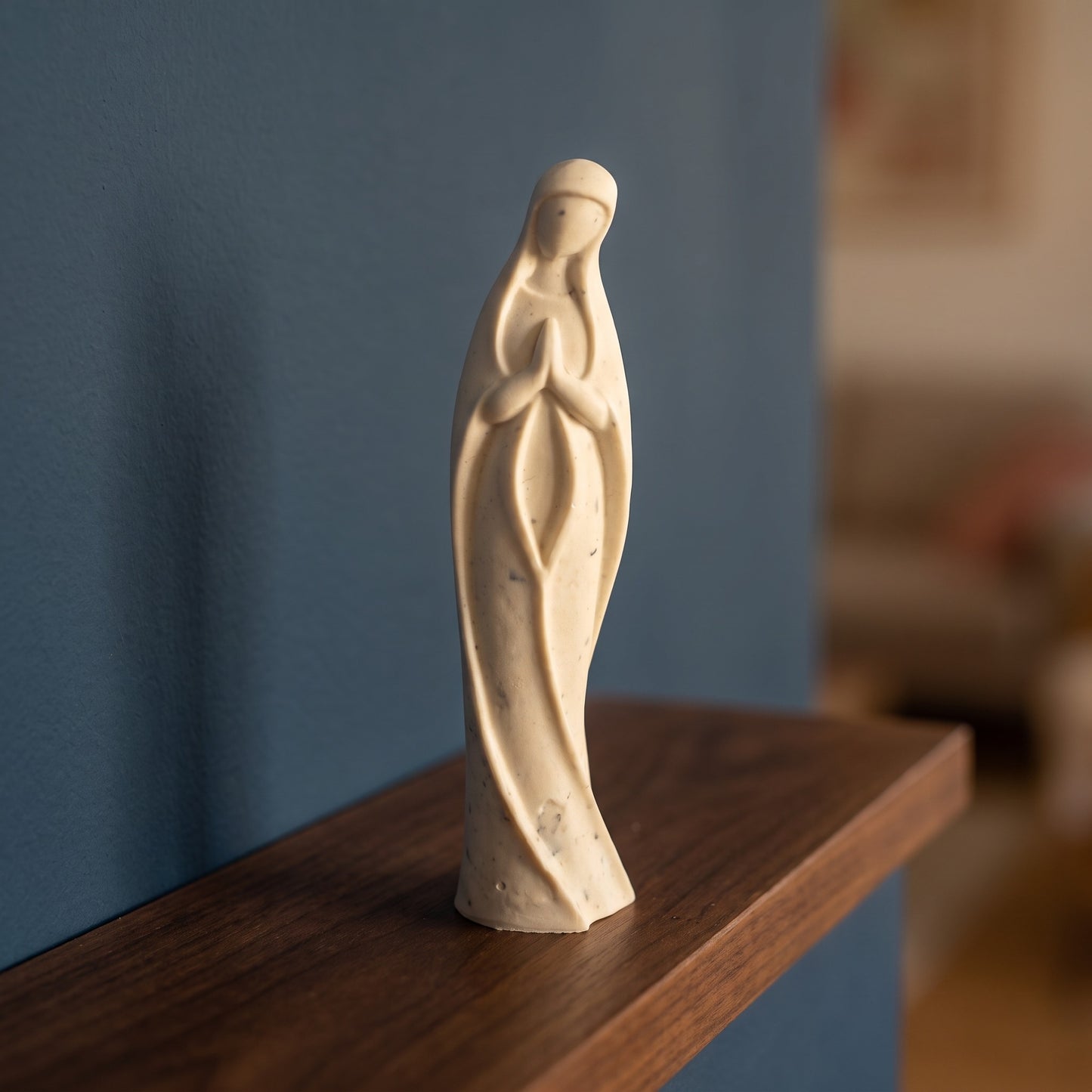Statuette artisanale de la Vierge Marie sur une étagère en bois